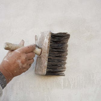 Kalking mur: Kost den tynne hvittekalken på veggen Kalking av mur: Kost den tynne hvittekalken på veggen